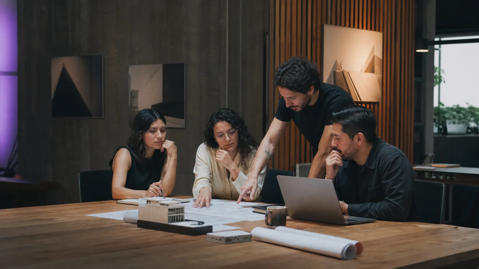 Equipo de consultoría ArchiLogic colaborando alrededor de planos y una computadora